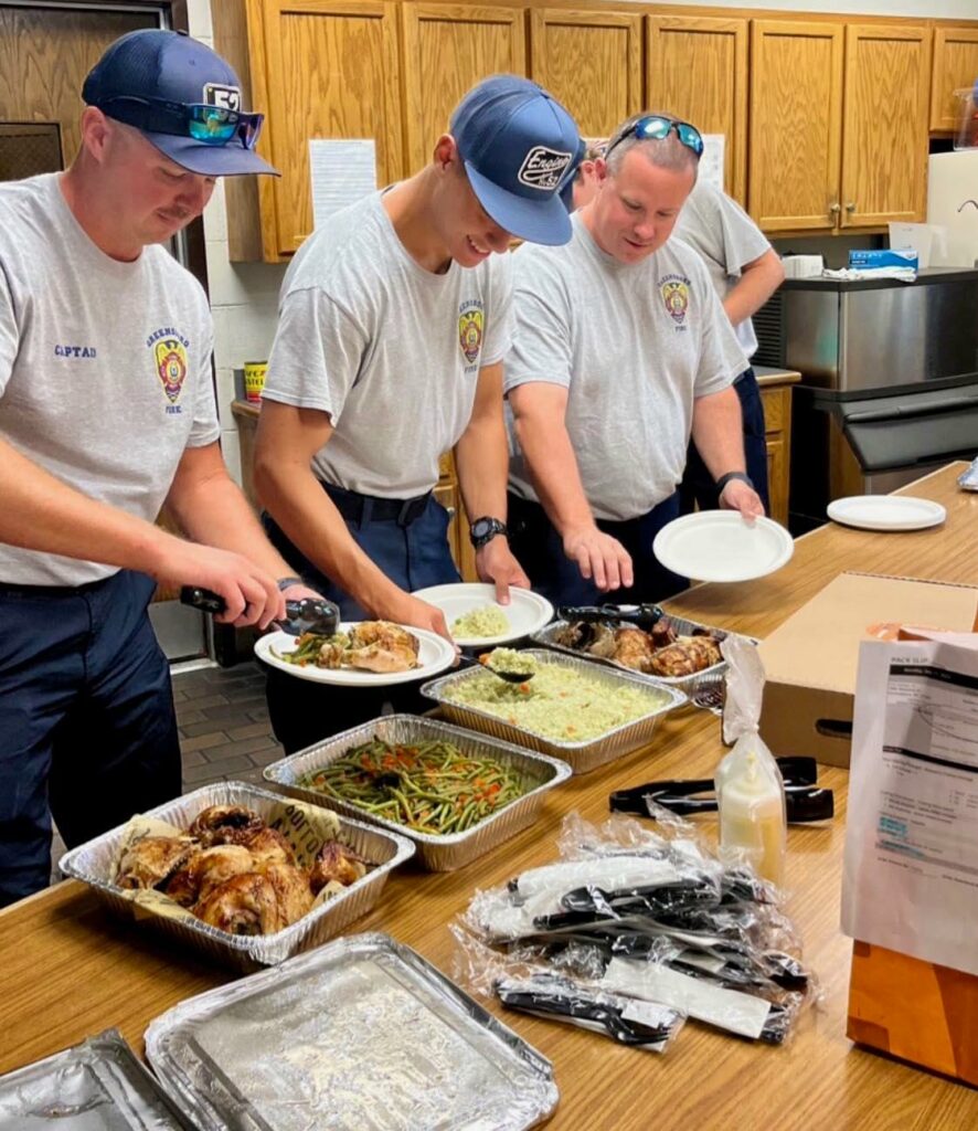 A group of men in matching shirts serving food.